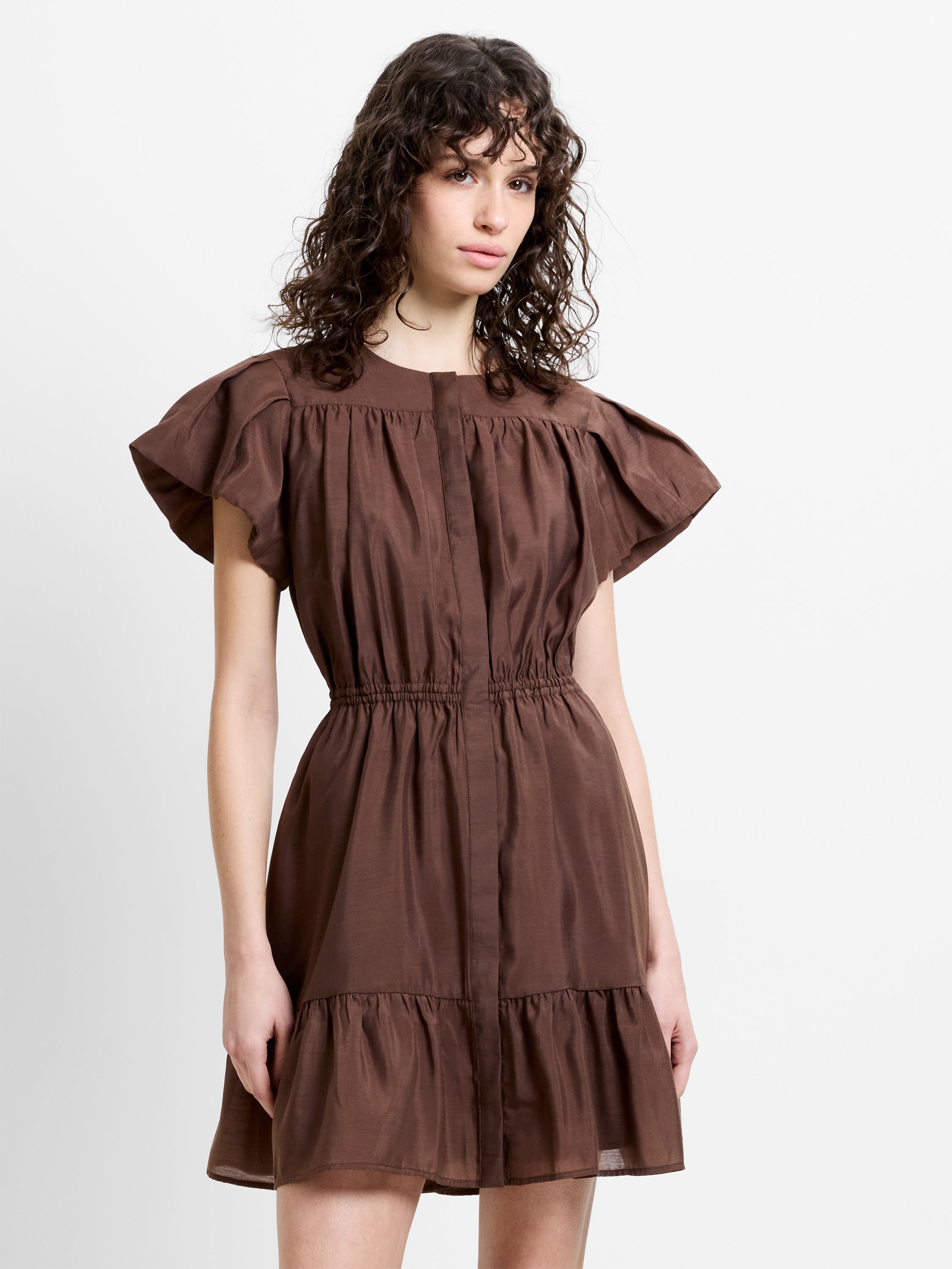 Woman wearing a chocolate brown mini dress with flutter sleeves and gathered waist detailing
