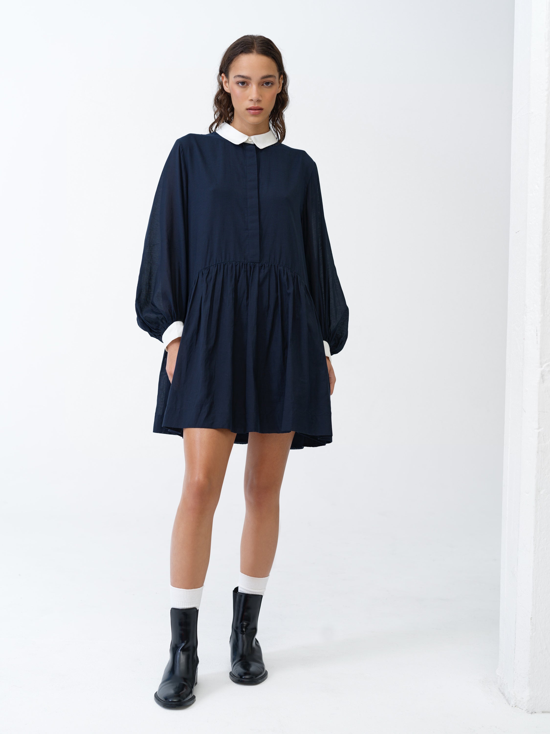 Woman wearing a long bishop sleeve, navy shirt dress with a contrasting white collar and cuffs