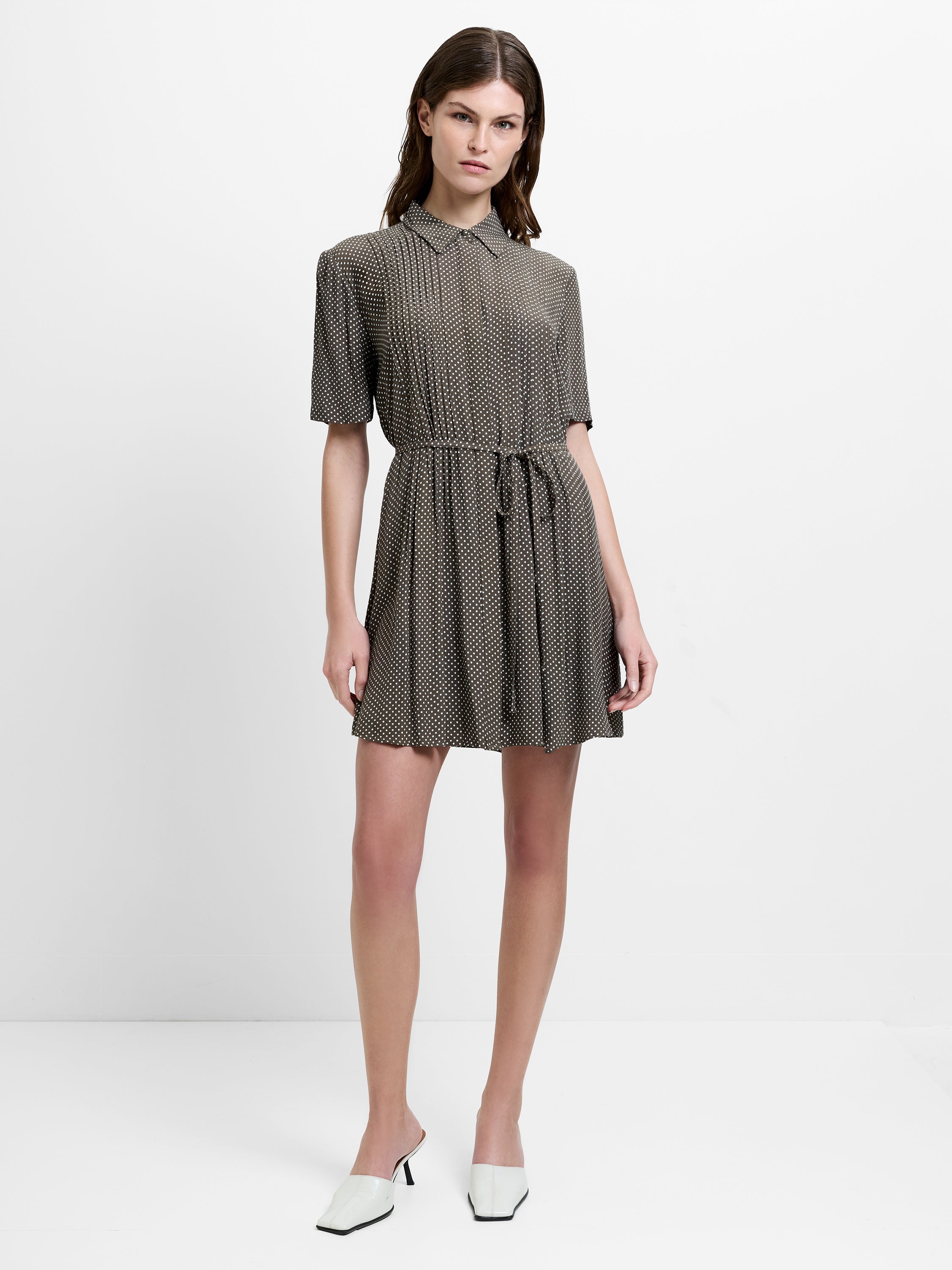 Woman wearing a flowy mini shirt dress, with short sleeves and a shirt collar in a delicate polka dot print