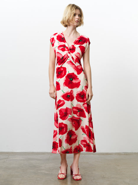 Woman wearing a floral poppy print midi dress, with cap sleeves, a V neckline and a twist knot front detail