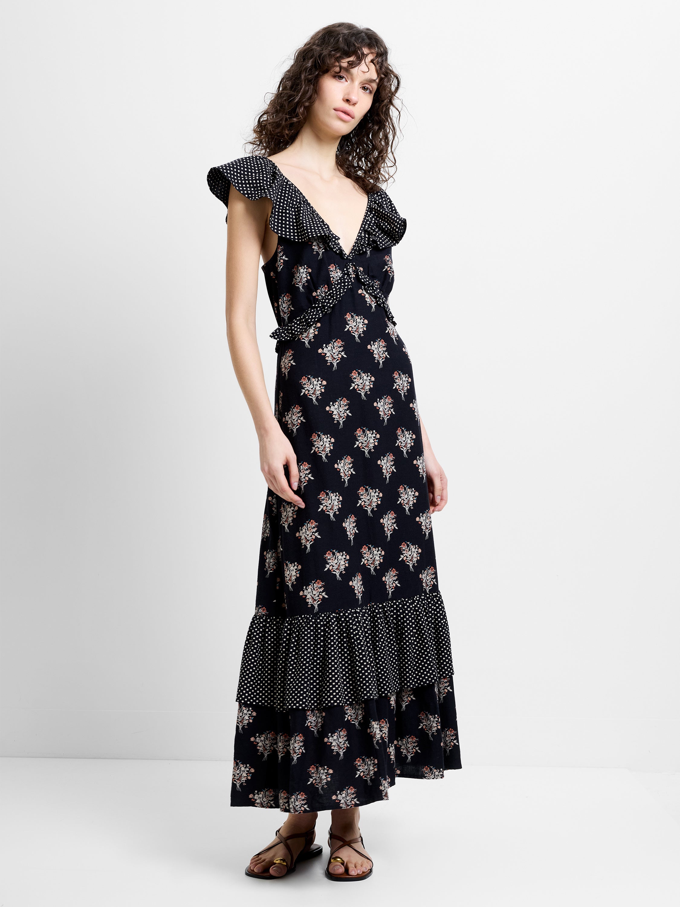 Woman wearing a floral and spot black printed midi dress with ruffle sleeves and a deep V neckline