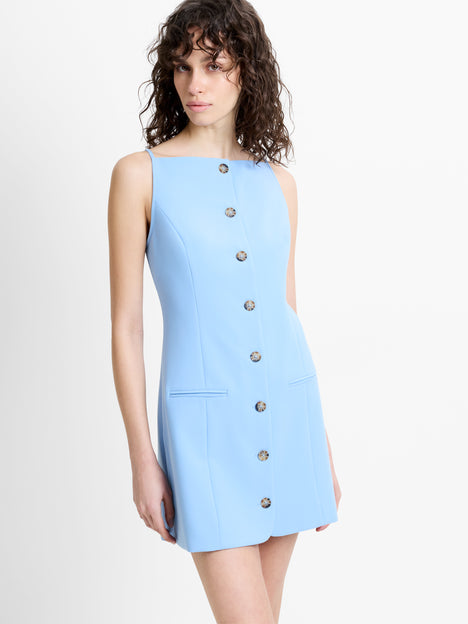 Woman wearing a light blue tailored mini dress, with a square neckline, straps and faux button down detailing