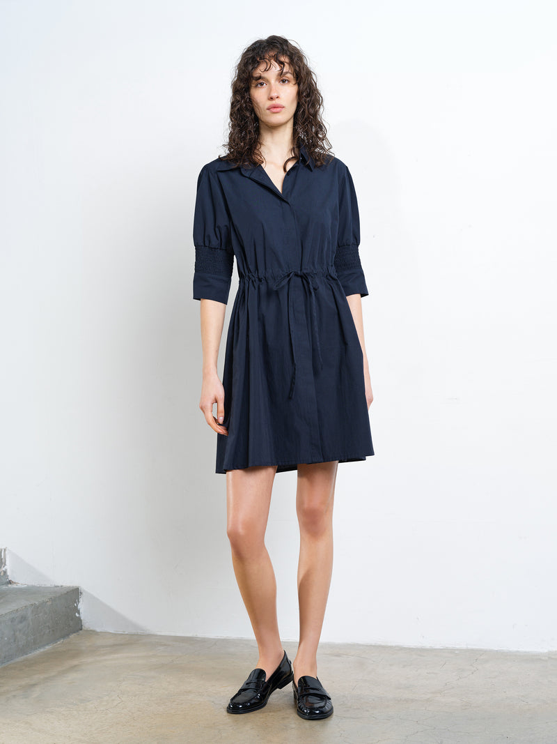 Woman wearing a navy blue mini shirt dress with a drawstring waist