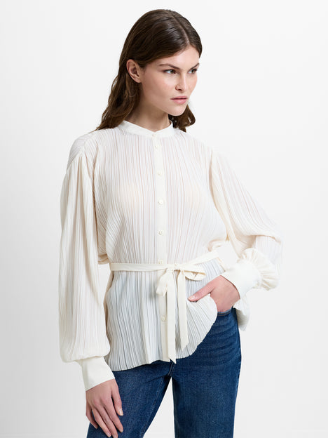 Woman wearing a cream blouse with long balloon sleeves and a tie belt