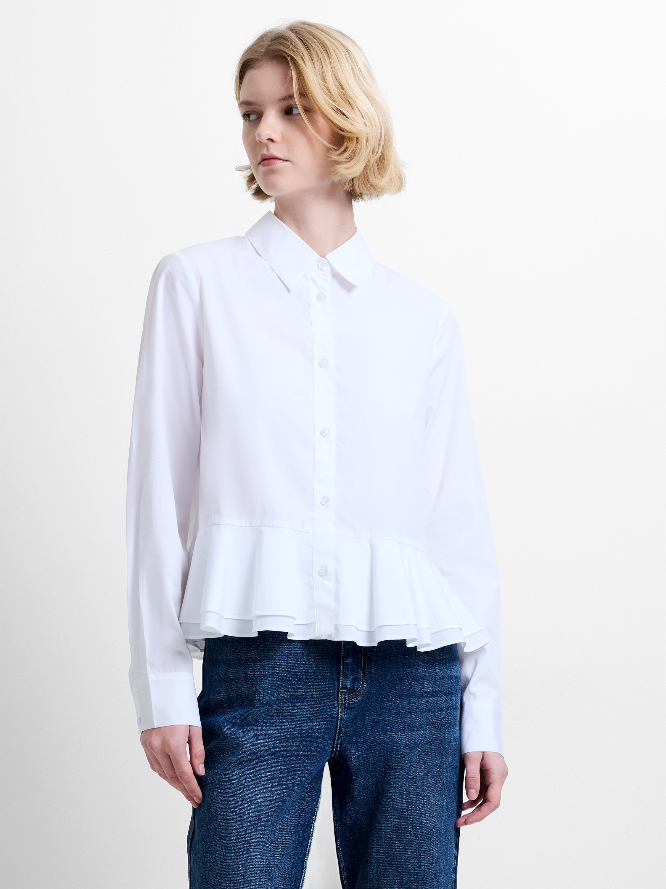 Woman wearing a white long sleeve shirt with a ruffled hem