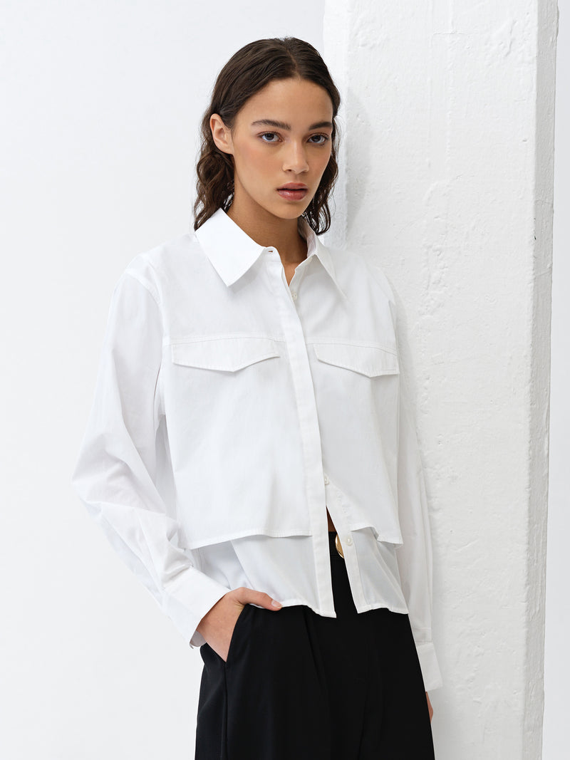 Woman wearing a long sleeve white double layered shirt with two faux pockets