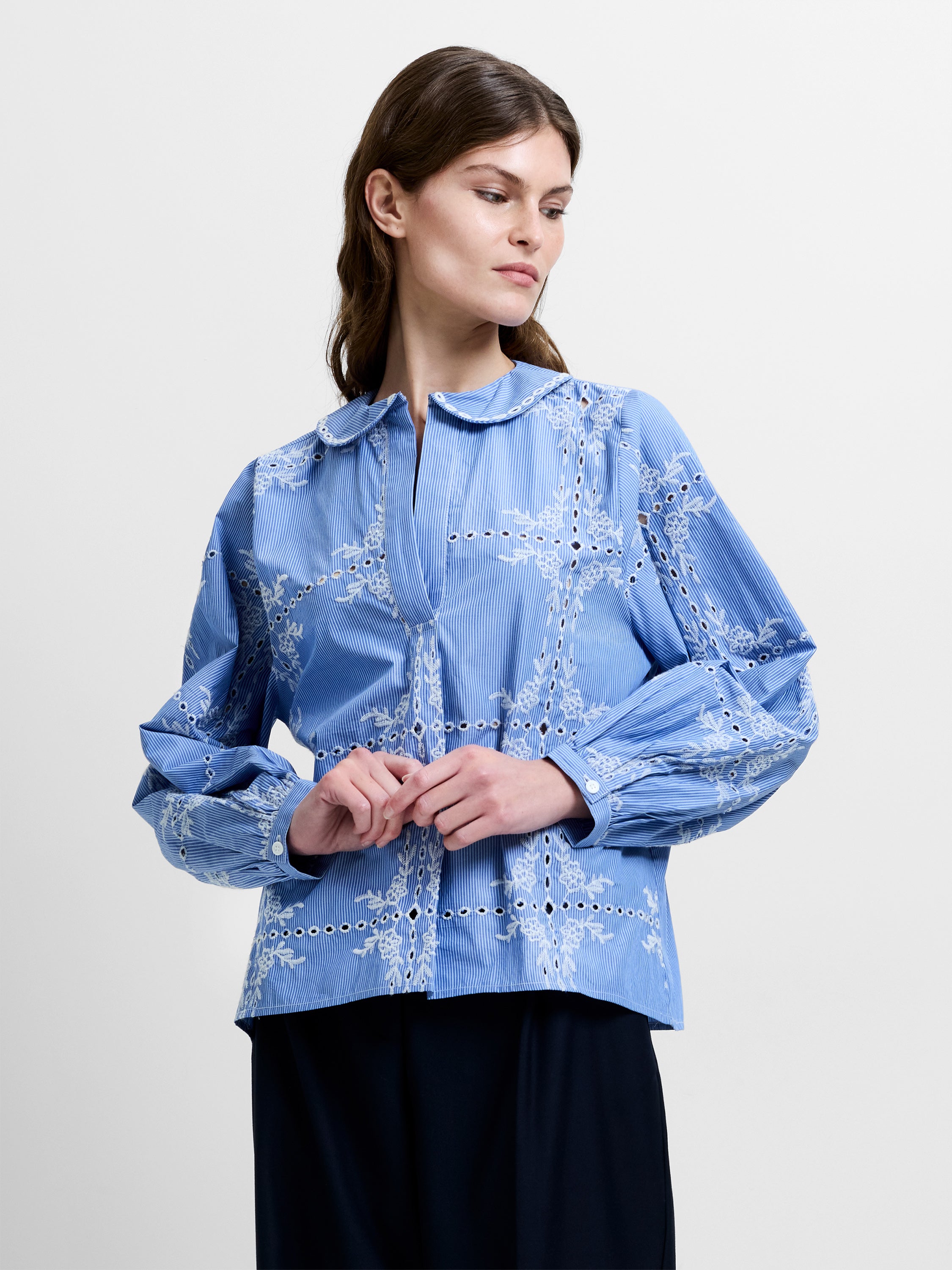 Woman wearing a blue embroidered long sleeve blouse with a peter pan collar