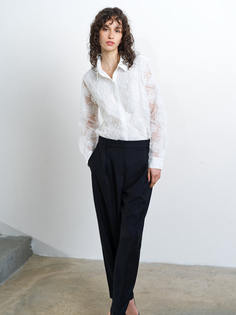 Woman wearing a white floral lace shirt with sheer long sleeves