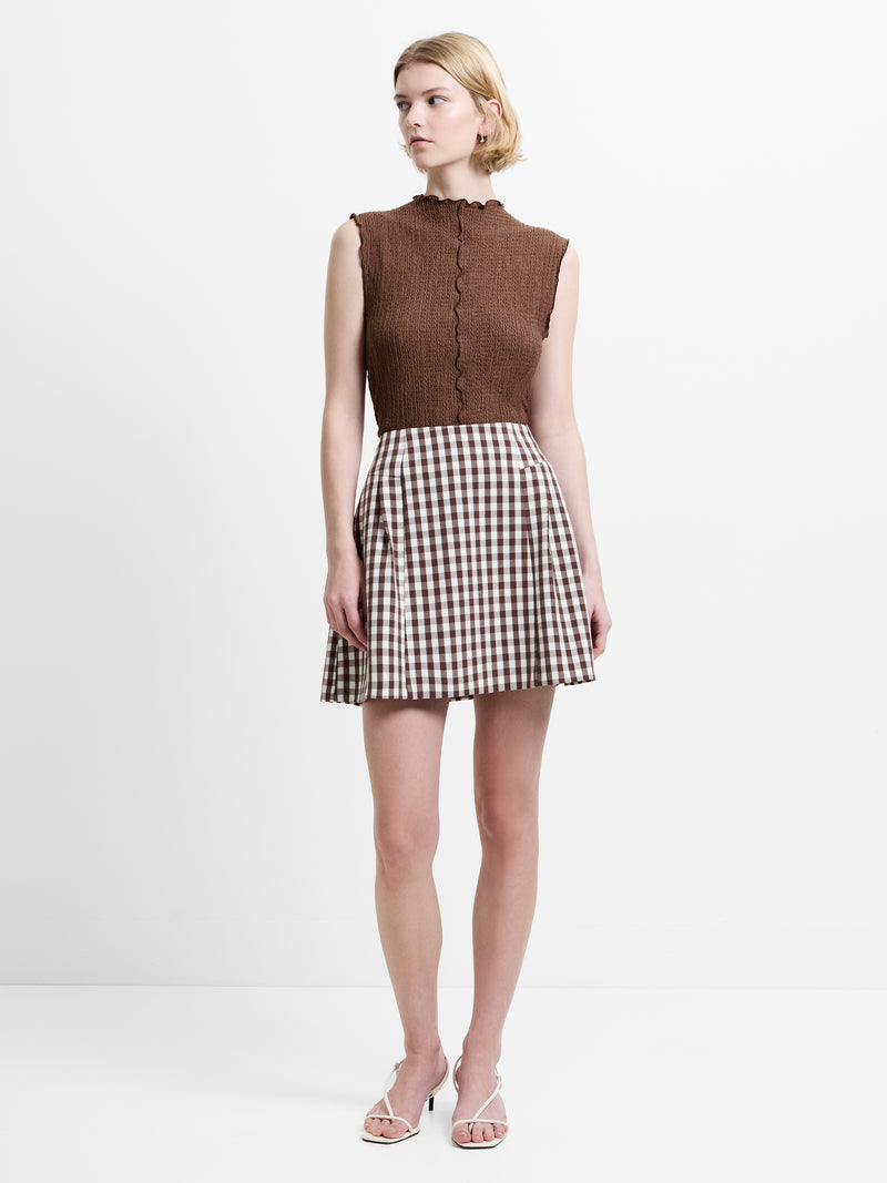 Woman wearing a brown and white gingham mini skirt with side pleats