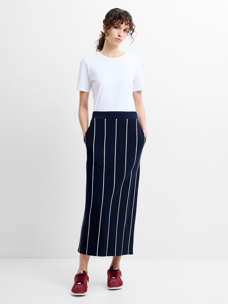 Woman wearing a white t-shirt and a navy pinstripe midi skirt with pockets