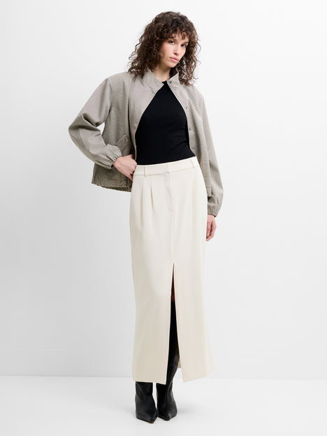 Woman wearing a black top, grey jacket and a cream front slit midi skirt