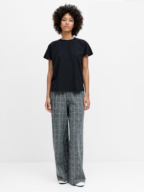 A woman wearing grey full length, wide leg trousers with an elasticated waistband and a subtle checked pattern. 
