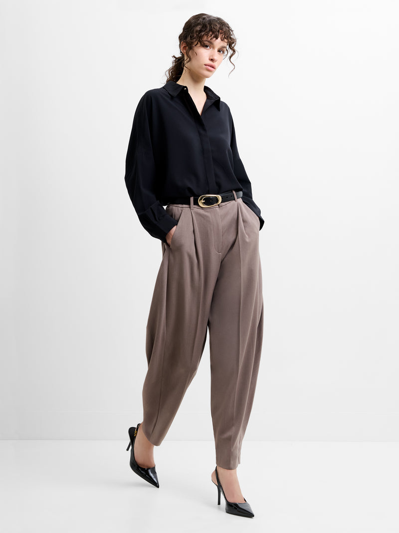 Woman wearing a black shirt and taupe brown tapered trousers