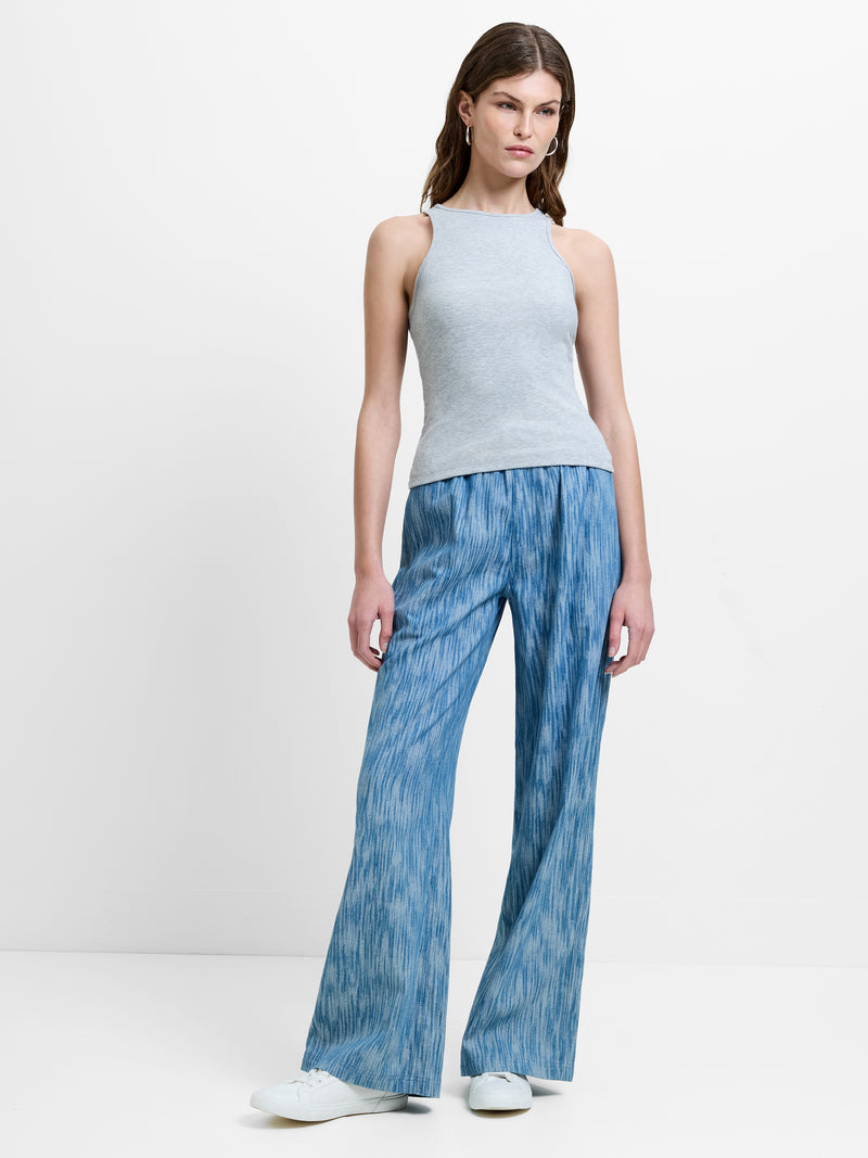 Woman wearing a grey sleeveless tank top with wide leg elasticated waist trousers in a blue jacquard print