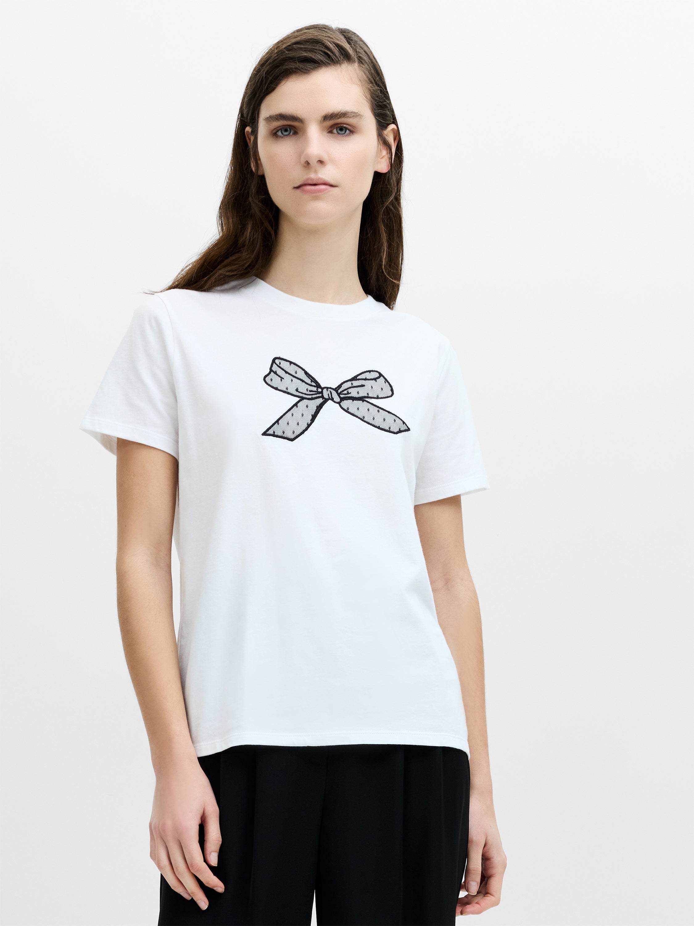 A woman wearing a white regular fit T-shirt with a crew neckline, short sleeves and a mesh bow detail.