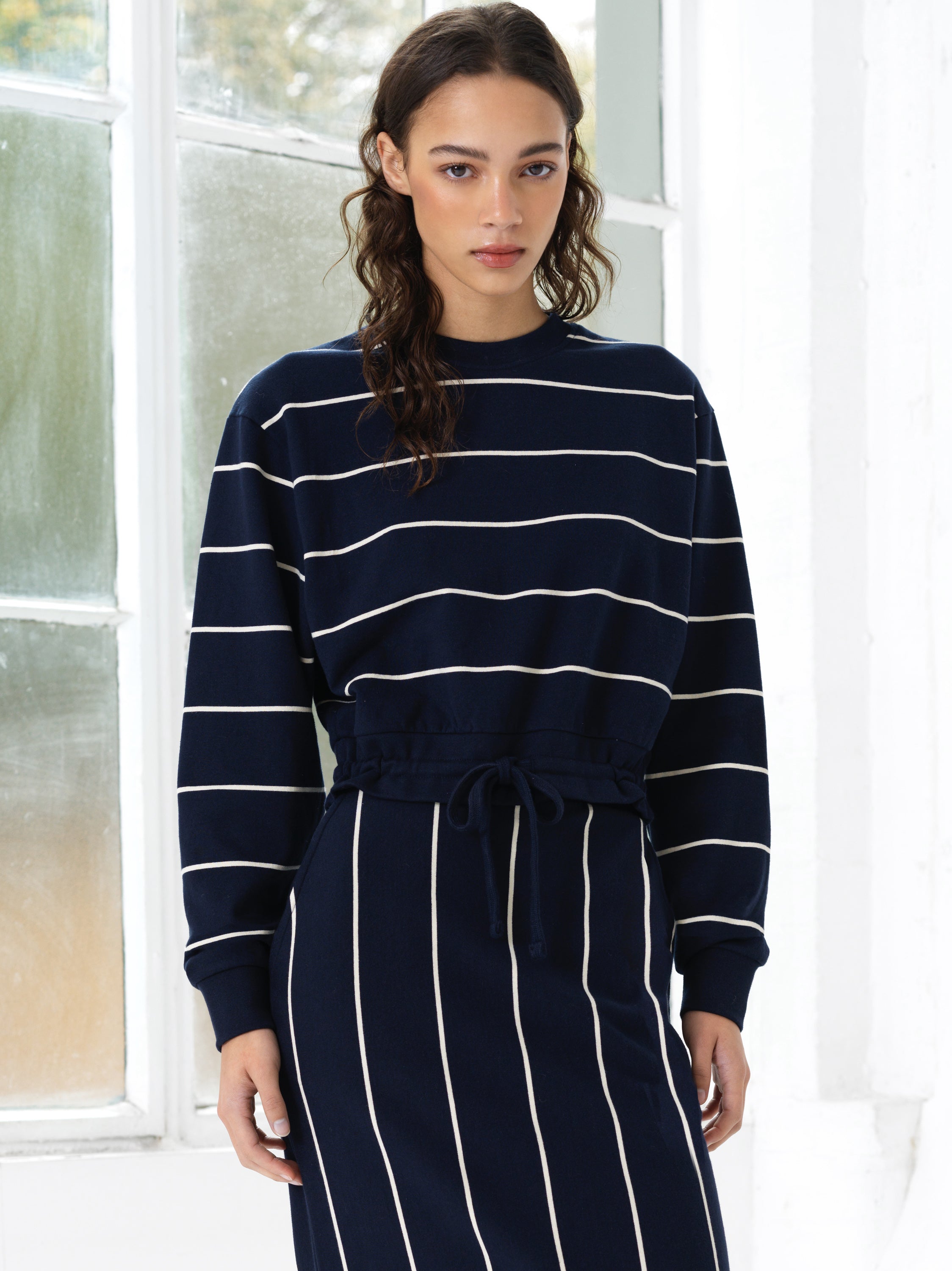 Woman wearing a navy and white striped drawstring hem top with a matching skirt
