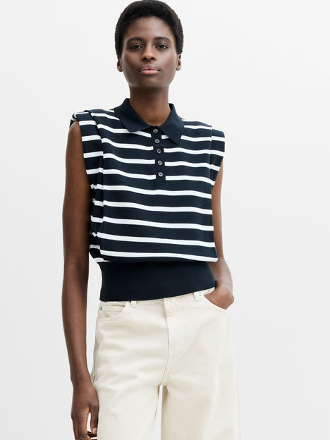 A woman wearing a sleeveless striped navy blue collared knit vest, with a button placket and a fitted ribbed hem.