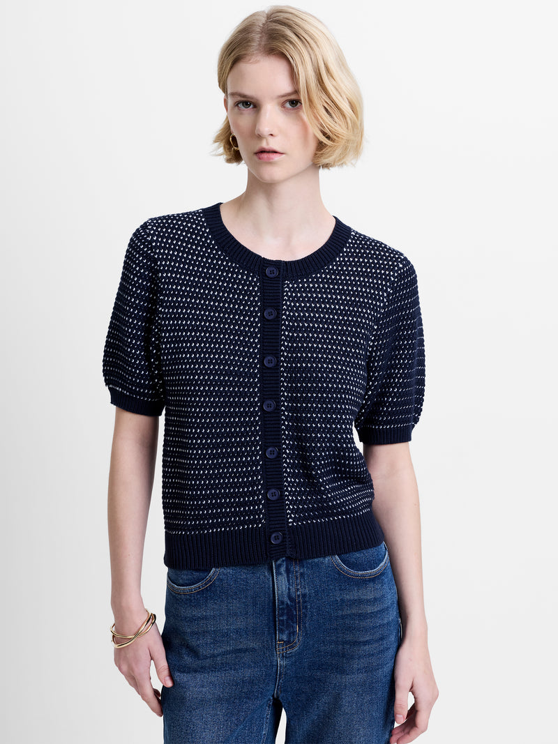 Woman wearing a navy, button down knitted top with short puff sleeves and a round neckline