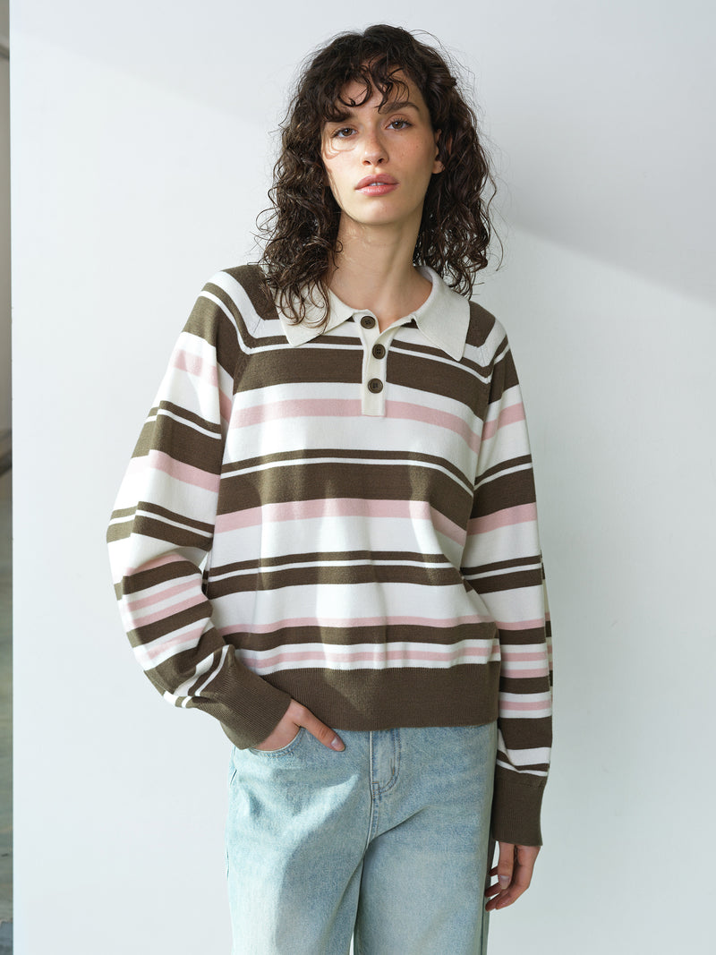 Woman wearing a cream, pink and khaki striped knitted polo top, with long raglan sleeves and a buttoned placket