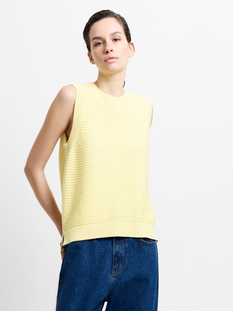 Woman wearing a purl stitch knitted sleeveless pale yellow tank top with a crew neckline