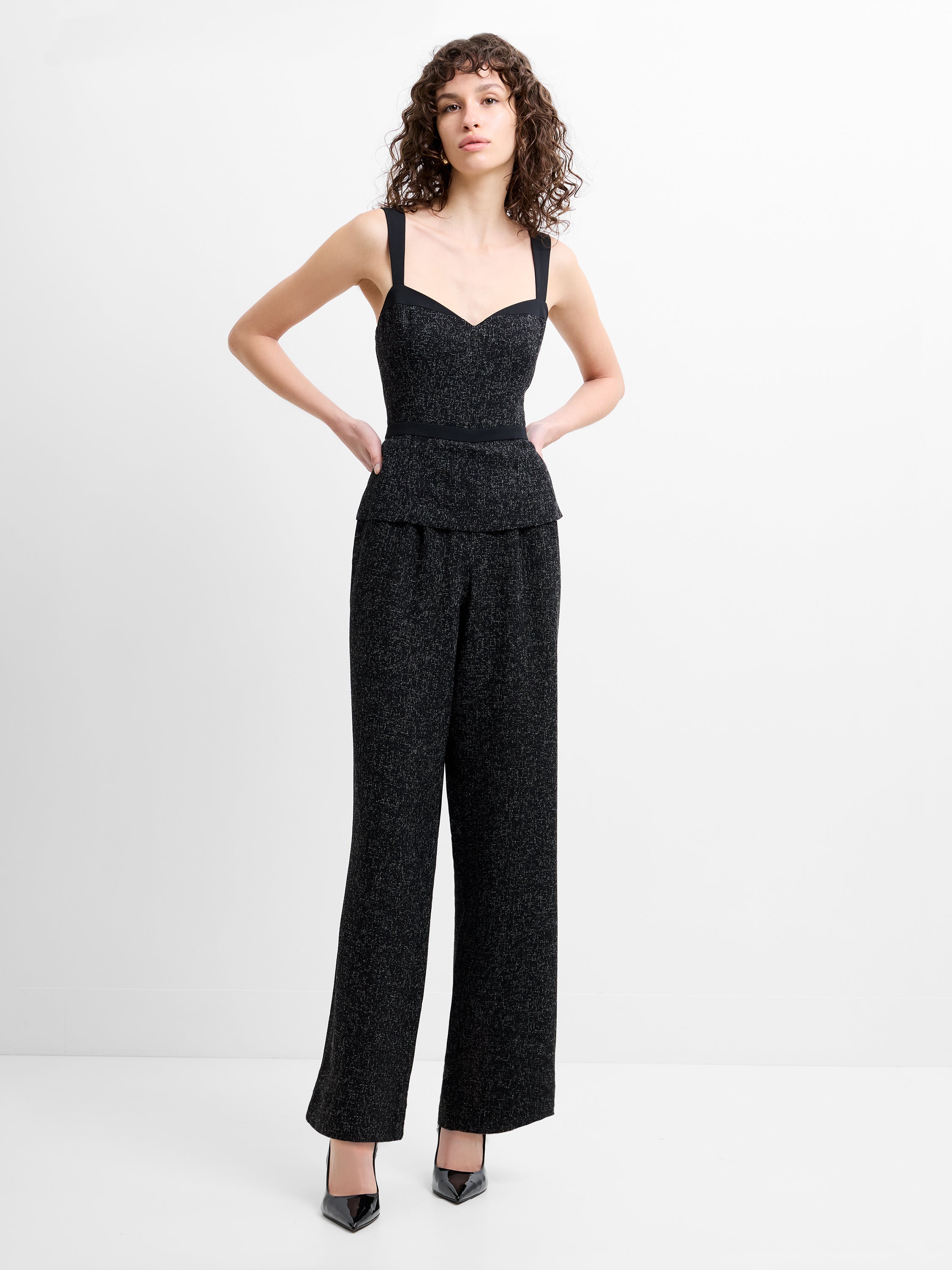 Woman wearing a black wide leg jumpsuit with straps and a sweetheart neckline